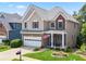 Well-manicured lawn and landscaping accent this two-story home with a two-car garage at 180 Mirramont Lake Dr, Woodstock, GA 30189