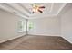 Large main bedroom with tray ceiling, cozy carpet, and bright windows that let in natural light at 180 Mirramont Lake Dr, Woodstock, GA 30189