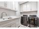 Modern laundry room with white cabinetry, quartz countertop, stainless steel sink, and appliances at 10635 N Edgewater, Johns Creek, GA 30097