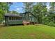 Back exterior view of the two-story green home, featuring a small deck and a lush green lawn at 1033 Justice Nw Ln, Acworth, GA 30102