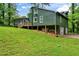 Back and side view of the exterior of the green home on a large lot, with a lush lawn at 1033 Justice Nw Ln, Acworth, GA 30102