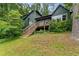 Two-story house with a wooden deck and stairs, surrounded by mature trees and greenery at 1033 Justice Nw Ln, Acworth, GA 30102