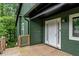 Close up of home's front door with wood porch, and green siding at 1033 Justice Nw Ln, Acworth, GA 30102