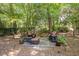 Outdoor seating area with a stone fire pit surrounded by lush greenery and tall trees at 2190 Stephen Long Ne Dr, Atlanta, GA 30305