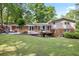Spacious backyard with a deck, patio, large grassy area, and mature trees at 225 River Springs Dr, Sandy Springs, GA 30328