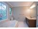 Bright bathroom featuring a tub, a decorative stained-glass window, and a vanity with modern fixtures at 214 Jamestown Ave, Jonesboro, GA 30236