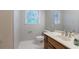 Neutral bathroom featuring a wood vanity, toilet, mirror, and natural light from the window at 214 Jamestown Ave, Jonesboro, GA 30236
