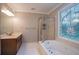 Elegant primary bathroom with tiled floor, tub, standing shower, unique window, and updated vanity at 214 Jamestown Ave, Jonesboro, GA 30236