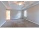 A bright primary bedroom has neutral walls, carpet, tray ceilings and an ensuite bathroom at 214 Jamestown Ave, Jonesboro, GA 30236