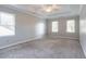 Bright, carpeted primary bedroom showcasing natural light, a ceiling fan, and a tray ceiling at 214 Jamestown Ave, Jonesboro, GA 30236