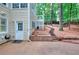 An exterior view of a home featuring a backyard door, security camera, and a landscaped yard with wood stairs and foliage at 1850 Noblin Ridge Way, Duluth, GA 30097