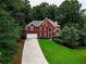 Two-story brick home with a long driveway, beautiful lawn, and surrounded by lush trees at 1850 Noblin Ridge Way, Duluth, GA 30097
