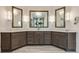 Bathroom vanity featuring a light countertop, dark cabinets, and well lit mirrors above dual sinks at 314 Caruso Ct, Sandy Springs, GA 30350
