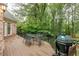 Wooden deck with a dining set and a grill, surrounded by lush greenery and offering a relaxing outdoor space at 314 Caruso Ct, Sandy Springs, GA 30350
