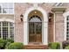 Grand entryway with a brick facade, arched door, and charming lantern sconces for a warm welcome at 314 Caruso Ct, Sandy Springs, GA 30350