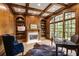Cozy home office boasts wood paneling, a decorative fireplace, large windows, and built-in bookshelves at 314 Caruso Ct, Sandy Springs, GA 30350