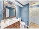 Bathroom featuring a decorative mirror, wood cabinet, toilet and walk in shower at 4817 Overland Dr, Powder Springs, GA 30127