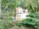 Charming brick home with bay window and covered porch surrounded by lush, mature landscaping and trees at 4817 Overland Dr, Powder Springs, GA 30127