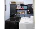 Well-organized laundry room featuring black and white appliances and overhead cabinets at 4218 Sandy Branch Dr, Buford, GA 30519