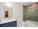 Modern bathroom features stone tile in shower, white hexagon tile floors, toilet and blue vanity at 2235 Birchtree Way, Marietta, GA 30062