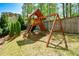 Wooden playset with slide and swings in a grassy, fenced backyard with mature trees at 2235 Birchtree Way, Marietta, GA 30062