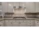 Close-up of a kitchen's granite countertop, white cabinets, tiled backsplash, and modern stainless steel range hood at 5327 Saville Nw Dr, Acworth, GA 30101