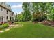 Wide backyard view showcasing a lush lawn, mature trees, a patio, and a serene waterfall feature at 4020 Devereux Chase, Roswell, GA 30075