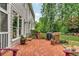 Backyard with a brick patio, lush lawn, mature trees, and a built-in grill area, ideal for outdoor living at 4020 Devereux Chase, Roswell, GA 30075