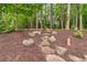 Landscaped backyard pathway with stone steps, mulch, and greenery, leading to a garden arch at 4020 Devereux Chase, Roswell, GA 30075