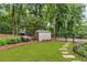 Spacious backyard with a shed, lush green lawn, stone path, and mature trees, perfect for outdoor activities at 4020 Devereux Chase, Roswell, GA 30075