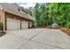 Exterior view of the side of a brick home featuring a two car garage, a large driveway, and a fenced yard at 4020 Devereux Chase, Roswell, GA 30075