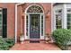 Inviting front door with transom window, flanked by sconces and potted plants at 4020 Devereux Chase, Roswell, GA 30075