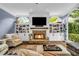 Bright living room with a stone fireplace, built-in shelves, and large windows overlooking lush greenery at 4020 Devereux Chase, Roswell, GA 30075
