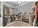 Spacious walk-in closet with custom shelving and rows of hanging rods offers lots of storage solutions at 4020 Devereux Chase, Roswell, GA 30075