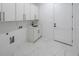 A modern laundry room boasts marble floors and white cabinets with black hardware at 2751 Camp Branch Rd, Buford, GA 30519