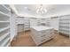 Spacious walk-in closet with custom shelving, island with storage, and modern chandelier at 2751 Camp Branch Rd, Buford, GA 30519