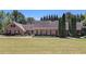 Charming brick home with a well-maintained lawn and mature trees under a clear sky at 1935 Northbrooke Ln, Dunwoody, GA 30338
