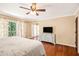 Bright primary bedroom with hardwood floors, TV, dresser, and balcony access overlooking the backyard at 1935 Northbrooke Ln, Dunwoody, GA 30338