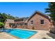 View of the pool and the large home with an outdoor living space and a brick exterior at 1935 Northbrooke Ln, Dunwoody, GA 30338