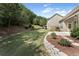 Large backyard with lush landscaping, stone retaining wall, and view of wooded area at 1955 Overlook Run Pl, Cumming, GA 30040
