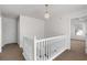 Bright hallway featuring white railings, beige carpet, and a stylish pendant light, creating an inviting transition space at 3448 Craggy Perch, Douglasville, GA 30135
