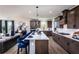 Open-concept kitchen flowing into the living area, featuring stainless steel appliances, an island with seating, and ample cabinetry at 4720 Montane St, Cumming, GA 30028