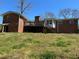 Exterior shot of the backyard showcasing a brick house with a second-story deck above the lawn at 5317 Kings Hwy, Douglasville, GA 30135