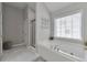 Bright bathroom with a large tub, tiled floor, and glass shower at 5613 Lancashire Ln, Cumming, GA 30041