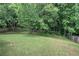 Spacious backyard featuring lush green grass surrounded by mature trees and a wood fence at 4975 Rockstone Way, Acworth, GA 30101