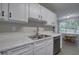 Bright kitchen featuring white cabinets, stainless steel appliances, marble countertops, and backyard views at 4975 Rockstone Way, Acworth, GA 30101