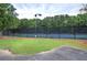 Community tennis court surrounded by fencing and lush trees; outdoor recreation and neighborhood amenities enhance living at 4975 Rockstone Way, Acworth, GA 30101
