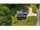 An aerial view of a home's manicured lawn, driveway, and roof, surrounded by mature trees and a nearby street at 125 Legacy Way, Oxford, GA 30054
