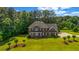 A stately brick home boasting a manicured lawn with mature trees and elegant architectural details at 125 Legacy Way, Oxford, GA 30054