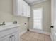 Laundry room with white cabinets, tile floors, and a window providing natural light at 125 Legacy Way, Oxford, GA 30054